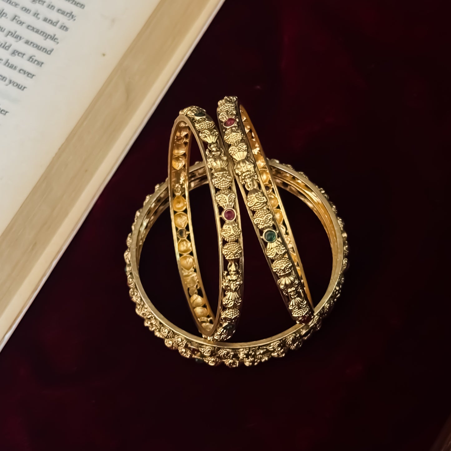Madhulika premium antique gold temple bangles featuring continuous rows of sculpted goddess lakshmi motifs pink and green stones