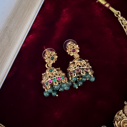 Hansani Temple premium antique gold long necklace set featuring a linked peacock chain a crescent chandbali pendant with red and green stones a dense bead fringe and matching dome jhumka earrings