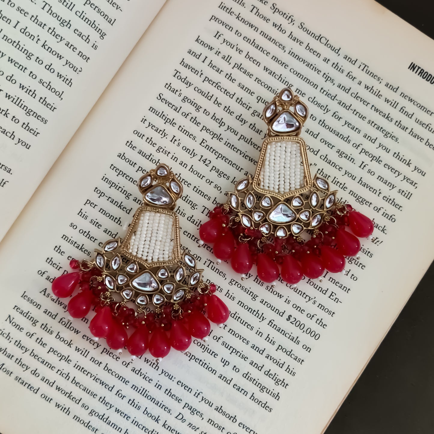 Khushi premium antique gold chandbali earrings featuring tear shaped studs seed pearl filled vertical panels crescent kundan medallions and a tiered fringe ending in translucent ruby pink beads
