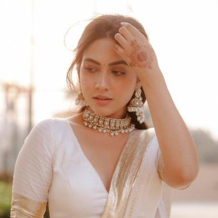Reem premium antique gold kundan broad choker necklace set featuring a central crescent flower rosette medallion multi strand woven white pearl bands and matching chandelier earrings with detachable multi layer sahara hair chains