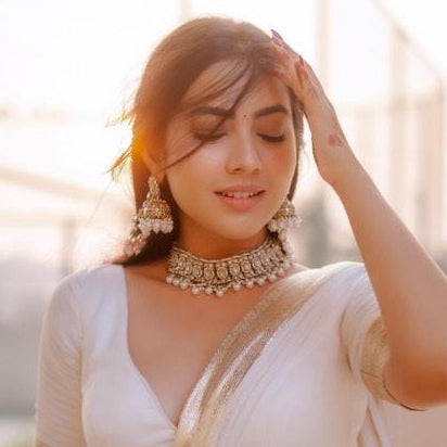 Reem premium antique gold kundan broad choker necklace set featuring a central crescent flower rosette medallion multi strand woven white pearl bands and matching chandelier earrings with detachable multi layer sahara hair chains