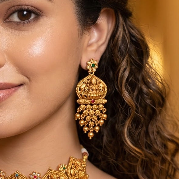 Swarna Temple premium antique gold long necklace set featuring a link strand with a large shield pendant showing goddess lakshmi and peacock motifs and matching tiered drop earrings