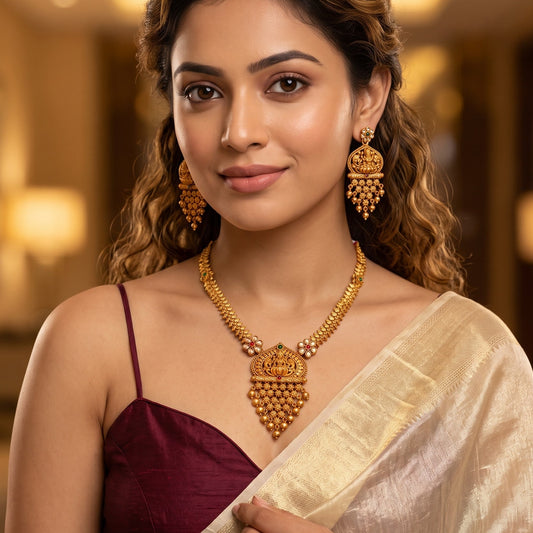 Swarna Temple premium antique gold long necklace set featuring a link strand with a large shield pendant showing goddess lakshmi and peacock motifs and matching tiered drop earrings