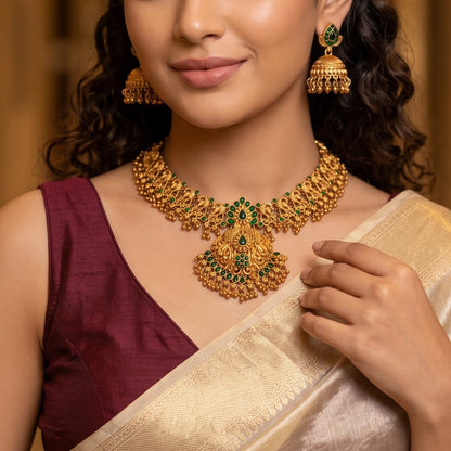 Nyra Temple premium antique gold long necklace set featuring a link strand with a large multi tiered shield pendant showing dancing peacock motifs and matching dome jhumka earrings