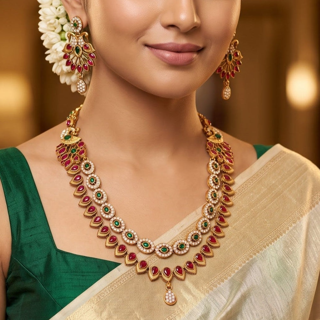 Aarna Temple premium antique gold double layer choker necklace featuring two linked tracks of concentric round green stones and a cascading bottom fringe of ruby red teardrop stones alongside matching chandelier earrings