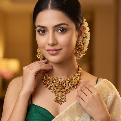 Avani Temple premium antique gold choker necklace featuring a broad central stacked pendant encrusted with pink and green kemp stones twin peacocks a gold ghungroo fringe and matching dome jhumka earrings