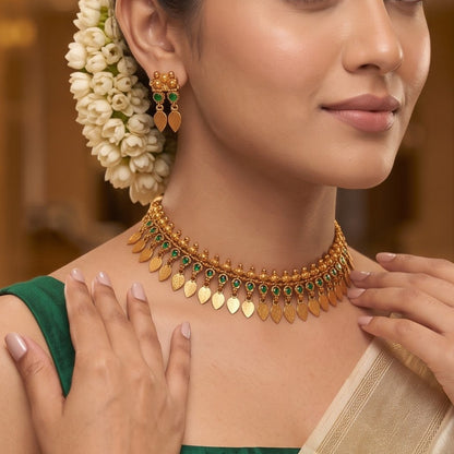 Kaira Temple premium antique gold choker necklace featuring a linear track of round emerald green kemp stones a top row of gold beads a bottom cascading fringe of flat coin leaf drops and matching earrings