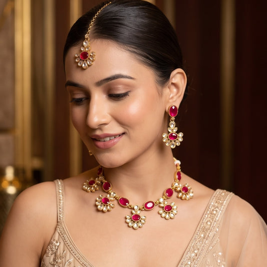Raisha premium antique gold kundan floral choker necklace set featuring a linked tracking of circular flower rosette dabi stones with central deep oval emerald green gems matching tiered drop earrings and maang tikka