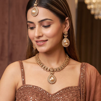 Multi Shazia Navratan premium antique gold kundan necklace set featuring a linear track of teardrop links a large central crimson ruby pear shaped pendant with green and yellow accents matching drop earrings and maang tikka