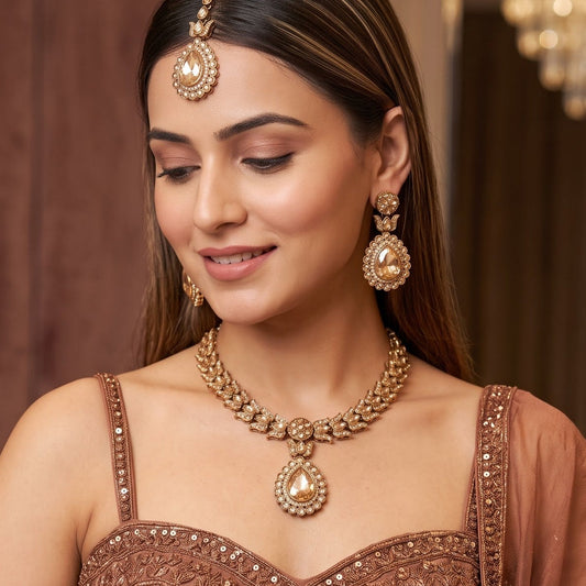 Multi Shazia Navratan premium antique gold kundan necklace set featuring a linear track of teardrop links a large central crimson ruby pear shaped pendant with green and yellow accents matching drop earrings and maang tikka