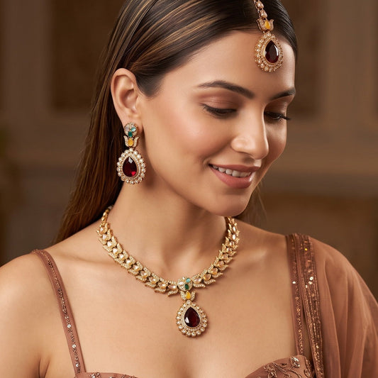 Multi Shazia Navratan premium antique gold kundan necklace set featuring a linear track of teardrop links a large central crimson ruby pear shaped pendant with green and yellow accents matching drop earrings and maang tikka