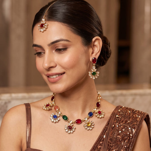 Raisha premium antique gold kundan floral choker necklace set featuring a linked tracking of circular flower rosette dabi stones with central deep oval emerald green gems matching tiered drop earrings and maang tikka