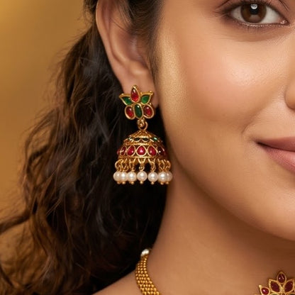 Amaira Temple premium antique gold choker necklace featuring a broad central diamond shaped plaque encrusted with pink and green kemp stones a dense micro pearl fringe and matching dome jhumka earrings
