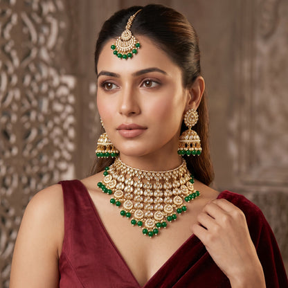 Shameena premium antique gold kundan plunging choker necklace set featuring multi tier tracks of clear dabi stones a dense cascading fringe of white pearls matching dome jhumka earrings and a crescent maang tikka